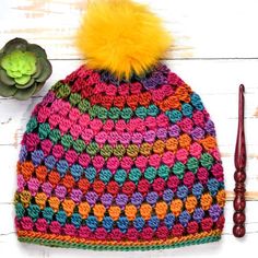 a crocheted hat with a yellow pom - pom