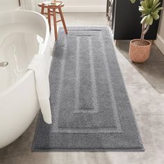 a bathroom with a bathtub and rugs on the floor