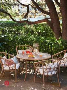 an outdoor table and chairs under a tree