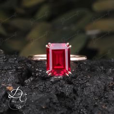 a red stone ring sitting on top of a rock