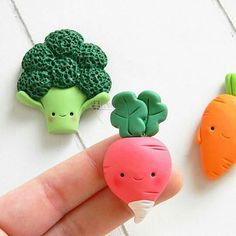 three broccoli, carrots and cauliflower magnets on a person's finger