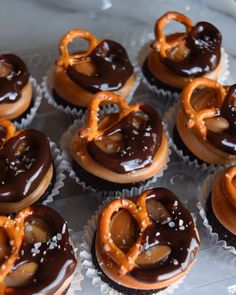 chocolate and pretzel shaped doughnuts are arranged in rows on a tray