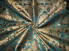 a blue and gold brocaded fabric with an intricate design on it's center