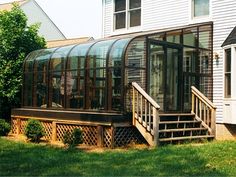 a house with a glass enclosed porch in front of it and stairs leading up to the second floor