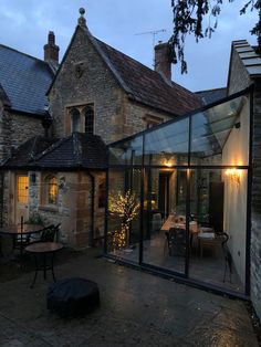 an outside patio area with tables and chairs at dusk, surrounded by stone buildings in the background