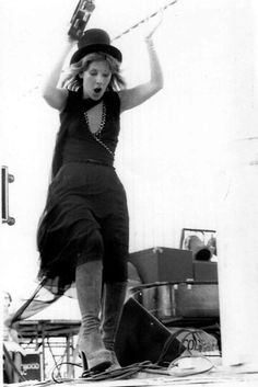 a woman in black dress and hat on skateboard