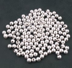 many silver balls are arranged on a black surface, with one ball in the middle