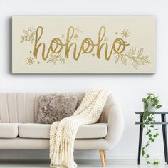 a living room with a white couch and gold foil lettering on the wall above it