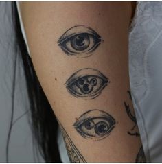 a woman's arm with tattoos on it and three different eyes in the middle