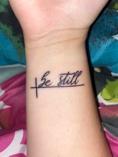 a woman's wrist tattoo with the word be still written on her left arm