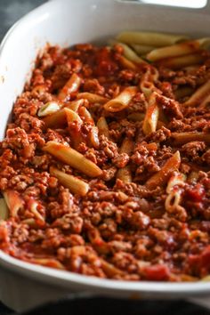 a white casserole dish filled with pasta and meat sauce on a black table