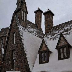 an old house with snow on the roof and chimneys in front of it's windows