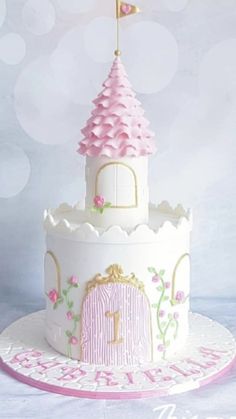 a white cake with pink frosting and a princess castle on top