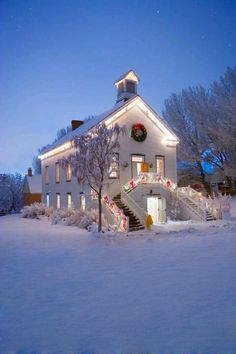 a white house with christmas lights on it's roof and stairs leading up to the front door