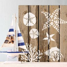 a small sailboat is sitting on the beach next to a wooden fence with sea life painted on it