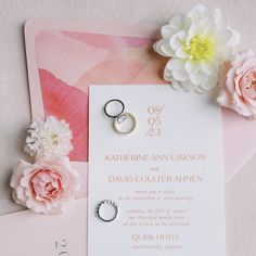 wedding rings and flowers on top of a pink card