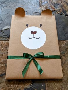 a brown paper bag with a bear face on it and green ribbon around the front