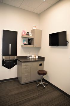 an empty room with a desk and television on the wall