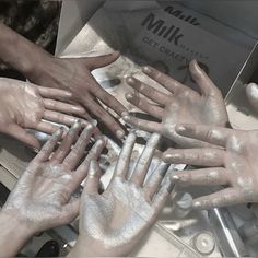 many hands are covered with white powder on top of each other in front of a box