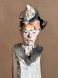 a ceramic sculpture of a woman wearing a hat