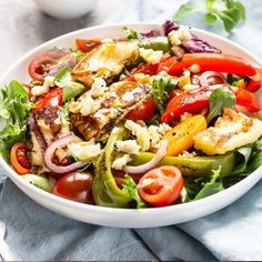 a white bowl filled with salad on top of a blue cloth next to a fork