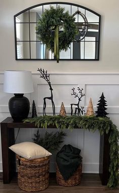 a table with christmas decorations on it and a mirror hanging above the table in front of it