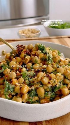 a white bowl filled with chickpeas and broccoli on top of a wooden table