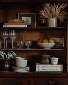 a wooden shelf filled with dishes and glasses on top of each other next to books