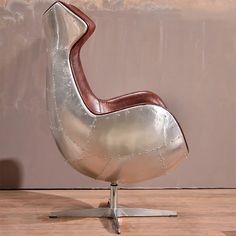 a silver and brown chair sitting on top of a hard wood floor next to a wall