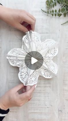 two hands are holding paper flowers on a table