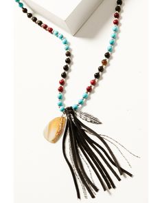 a necklace with feathers and beads on a white table next to a box that has a book