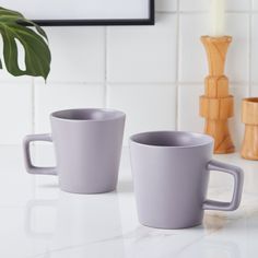 two coffee cups sitting on top of a white counter