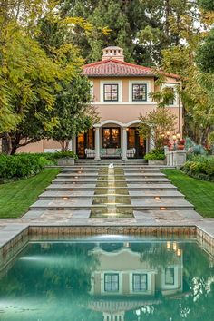 a large house sitting next to a pool in the middle of a lush green yard