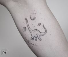 a small dinosaur tattoo on the right arm and shoulder, with planets in the background