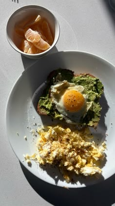 an egg and toast on a plate next to a bowl of orange juice with some sort of garnish