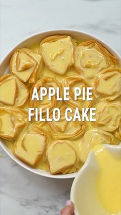 a bowl filled with apple pie filo cake next to a hand holding a spoon