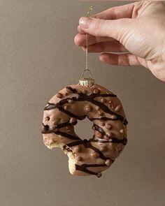 a hand holding a chocolate covered doughnut ornament