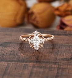 an oval shaped diamond engagement ring on top of a wooden table with fruit in the background