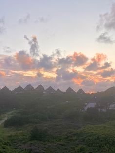 the sun is setting over some houses and hills