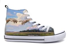 a pair of shoes painted with the creation of two hands reaching out to touch each other