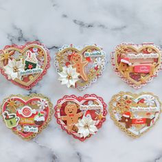 four heart shaped boxes with christmas decorations on them sitting on a marble countertop next to each other