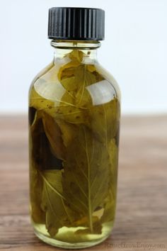 a bottle filled with leaves on top of a wooden table