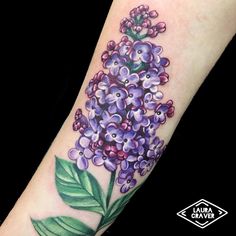 a tattoo with purple flowers and leaves on the arm, next to a yellow butterfly