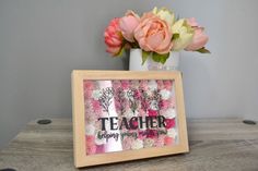 there is a vase with flowers in it and a sign on the table that says teacher