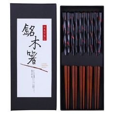 an open box with chopsticks in it and chinese writing on the front side