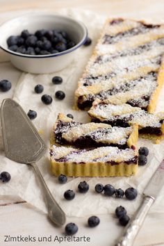 blueberry tart with powdered sugar on top and spoons next to it