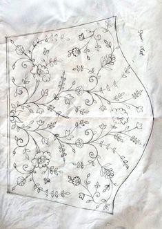 a piece of cloth with flowers and vines drawn on it, sitting on a sheet of paper