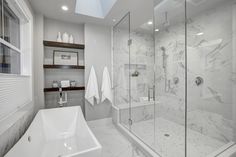 a bathroom with a walk in shower next to a bathtub and sink under a skylight