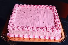 a cake with pink frosting and rosettes on it sitting on a table top