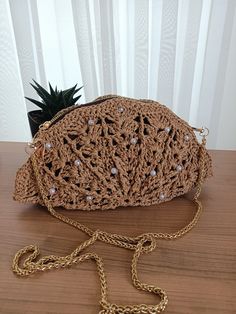 a crocheted purse sitting on top of a wooden table next to a plant